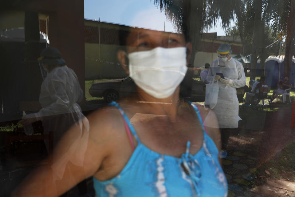 A woman in quarantine looks through the window to watch members of the National Mechanism to Prevent Torture (MNPT) visiting a school turned into a government-run shelter where citizens returning home are required by law to quarantine for two weeks and pass two consecutive COVID-19 tests as a preventive measure amid the COVID-19 in Ciudad del Este, Paraguay, Thursday, June 24, 2020. With only 7 million people, a stagnant economy, high poverty, and a weak public health system, Paraguay moved to slow coronavirus in March by closing borders and imposing the quarantine restrictions, along with closing schools and public events and declaring a nighttime curfew. (AP Photo/Jorge Saenz)
