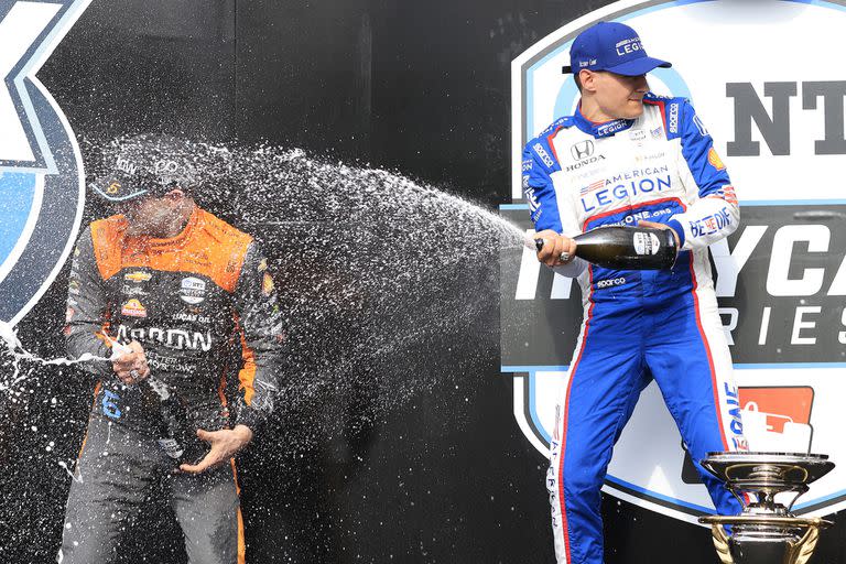 Ganador de la primera de las tres fechas que IndyCar desanduvo en el mítico autódromo de Indianápolis, Álex Palou festeja en lo más alto del podio su primer victoria en 2023; en la celebración baña de champagne al mexicano Pato O'Ward, piloto de Arrow McLaren