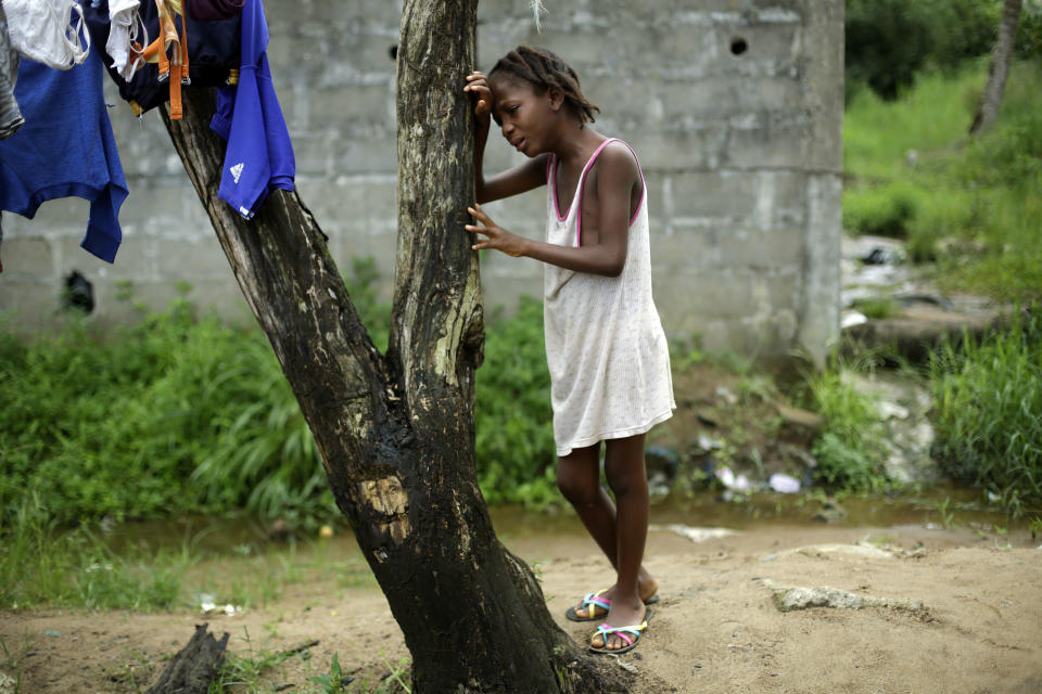 FILE - Mercy Kennedy, 9, cries as community activists approach her outside her home on 72nd SKD Boulevard in Monrovia, Liberia, on Oct. 2, 2014, a day after her mother was taken away by an ambulance to an Ebola ward. Liberians gathered Wednesday, March 13, 2024 to commemorate a decade since the country was first hit by a devastating outbreak of Ebola that killed thousands in West Africa, adding to the region's economic and political troubles. (AP Photo/Jerome Delay, File)