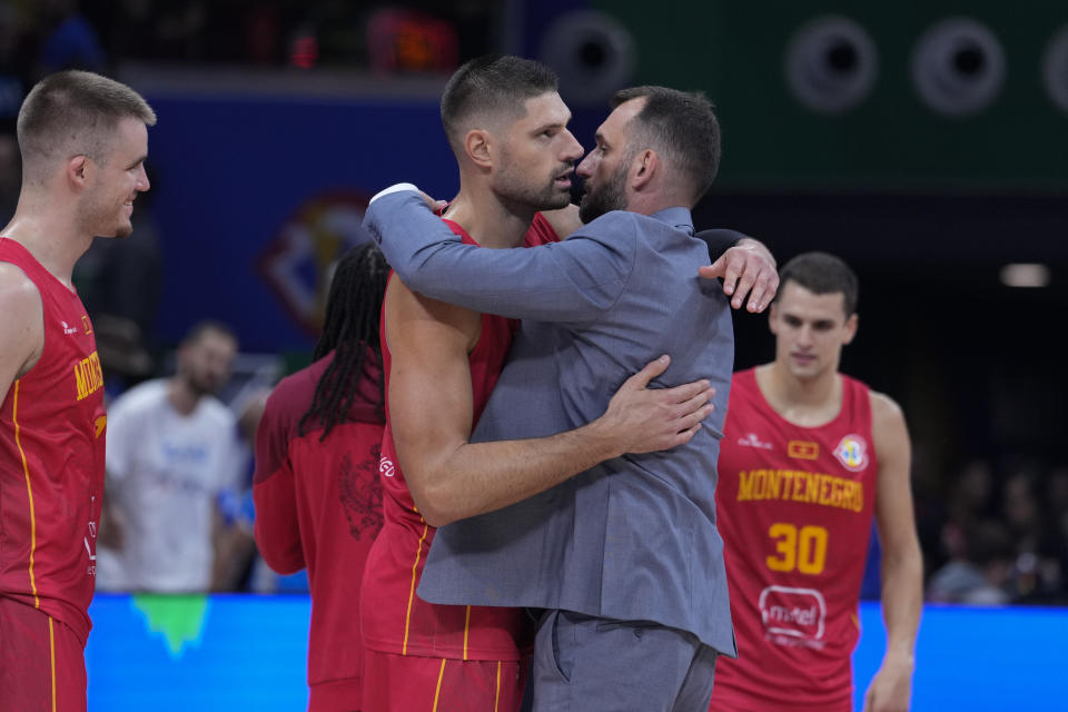 Montenegro center Nikola Vucevic (4) hugs coach Bosko Radovic during following a Basketball World Cup second-round match against Greece in Manila, Philippines Sunday, Sept. 3, 2023. Montenegro defeated Greece 73-69.(AP Photo/Michael Conroy)
