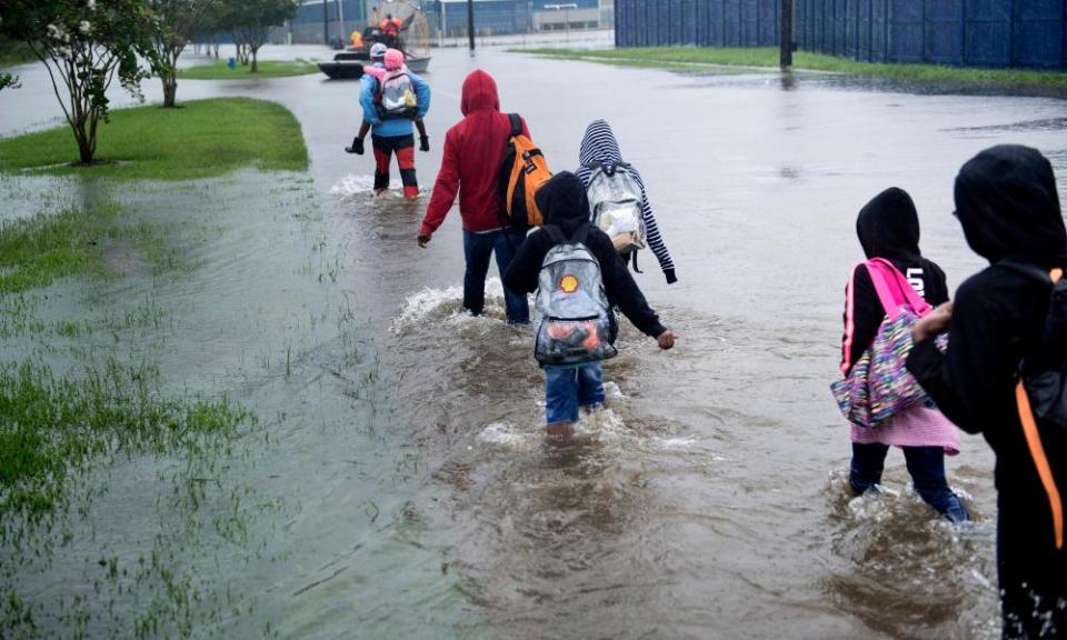 People walk to a Harris County Sherif airboat while escaping a flooded neighborhood during the aftermath of tropical storm Harvey.