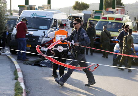 An Israeli policeman walks at the scene where a Palestinian stabbed and killed an Israeli soldier at a petrol station before he was shot dead by soldiers near the West Bank village of Khirbit Al-Misbah between Jerusalem and Tel Aviv November 23, 2015. REUTERS/Ammar Awad