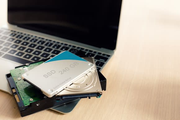 A laptop computer with storage drives lying on top of the keyboard.