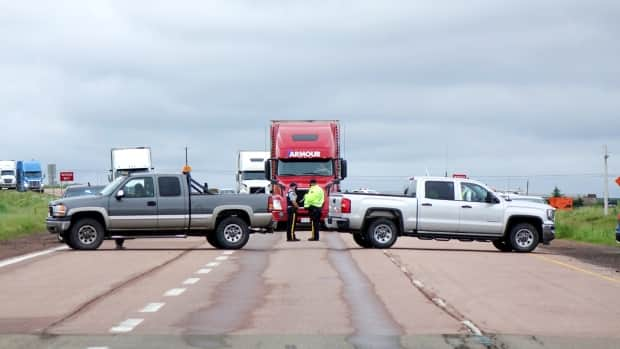 RCMP officers stand at the closed Nova Scotia-New Brunswick border when it was blocked by protesters this week. Police say some trucks carrying essential goods were allowed through the blockade. (Jonathan Villeneuve/CBC - image credit)