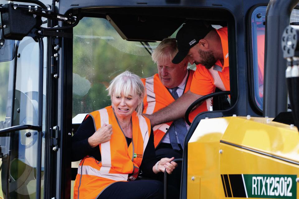 Britain's Prime Minister Boris Johnson (R) and Britain's Culture Secretary Nadine Dorries (L) sit in mole plough during a visit of the Henbury Farm in north Dorset, on August 30, 2022 as Wessex Internet company is laying fibre optics in the field. - Boris Johnson's visit marks a new data showing that 70 percent of the United Kingdom is now benefiting from gigabit broadband coverage. (Photo by Ben Birchall / POOL / AFP) (Photo by BEN BIRCHALL/POOL/AFP via Getty Images)