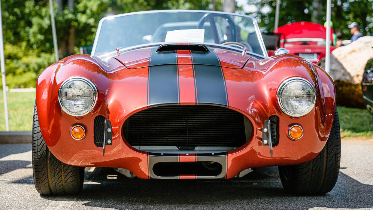 Wesley Chapel, North Carolina - July 27, 2019: Onlookers pass a Shelby Cobra on display at the Rock N Roller Event at Dogwood Park (Wesley Chapel, North Carolina - July 27, 2019: Onlookers pass a Shelby Cobra on display at the Rock N Roller Event at D.
