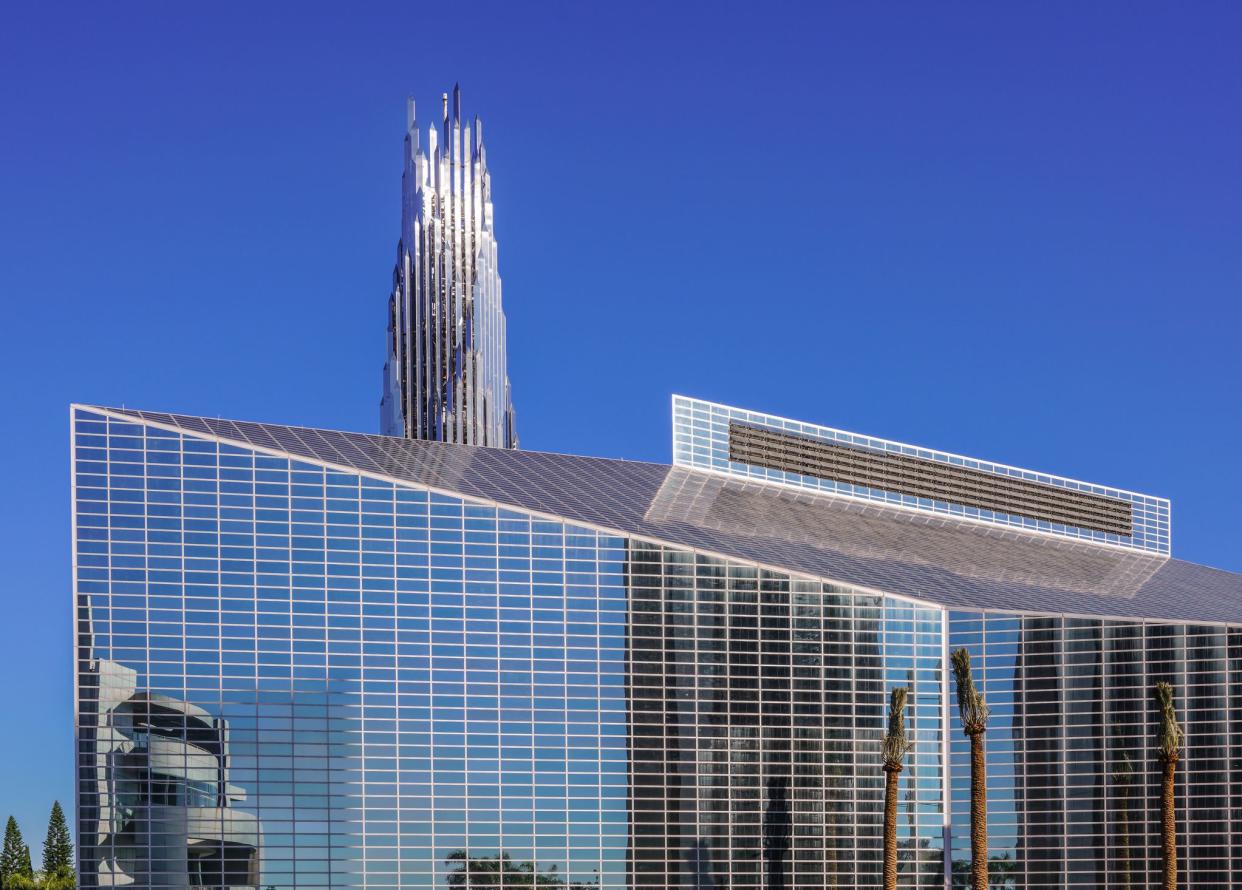 Garden Grove, California, USA - December 13, 2018: Crystal Christ Cathedral. Closeup of Church building and Crean Tower against blue sky. Cultural Center reflected in wall.