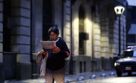 A man reads a newspaper as he walks in Buenos Aires' financial district early August 1, 2014. REUTERS/Marcos Brindicci