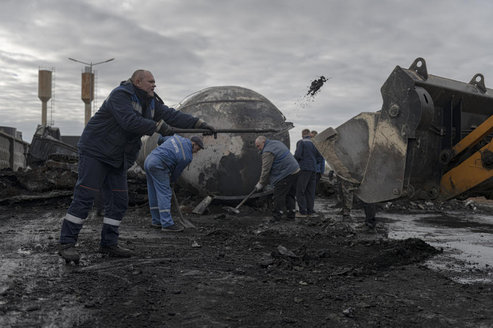 Workers clean up at a fuel depot hit by Russian missile in the town of Kalynivka, about 30 kilometers (18 miles) southwest of Kyiv, Ukraine, Thursday, Oct. 27, 2022. Environmental damage caused by Ukraine's war is mounting in the 8-month-old conflict, and experts warn of long-term health consequences for the population. (AP Photo/Andrew Kravchenko)