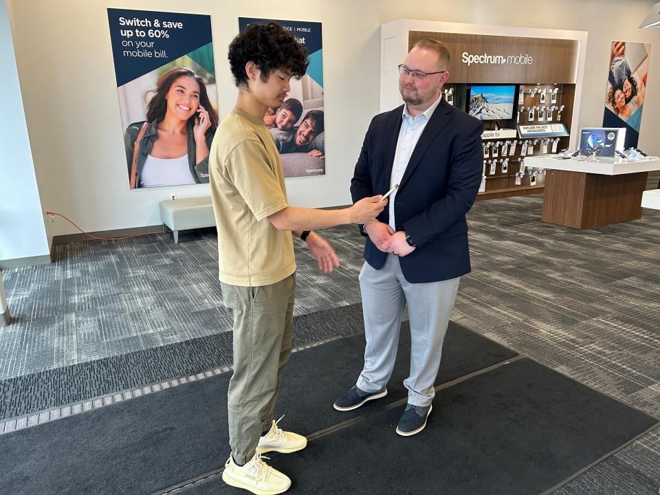 Trent Gobble, left, tries out Charter Communications/Spectrum's pilot ASL Video Relay Service Interpreter program alongside the Henrietta store's territory manager Josh Berbs in April 2024.