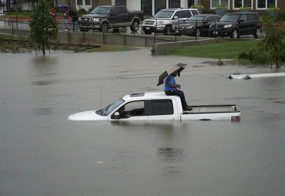 A man sits on top of a truck on a flooded road, Sept. 19, 2019, in Houston. Members of the Houston Fire Dept. brought him a life jacket and walked him to dry land. Throughout Texas and Louisiana, the remains of Tropical Depression Imelda kept bringing rains and flooding. (Photo: Melissa Phillip/Houston Chronicle via AP)