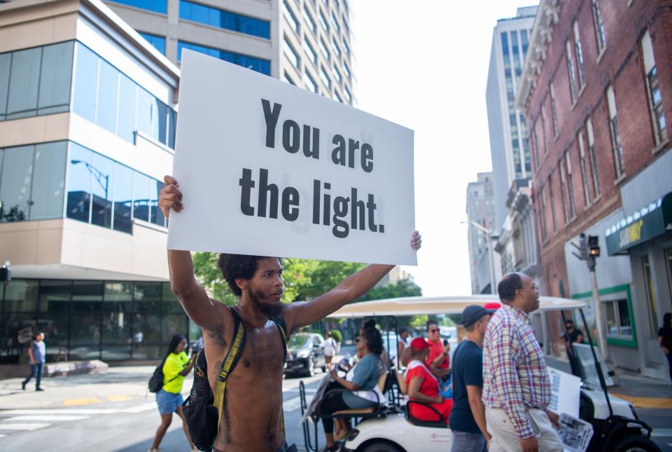 Allen DeBerry marches through Rep. John Lewis Way, holding a sign "you are the light" in Nashville, to the Ryman Auditorium, Saturday, July 23, 2022. 