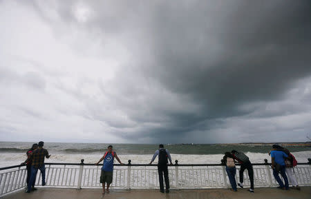 People look at the rough sea on a bridge as rainy clouds gather above during the monsoon period in Colombo, Sri Lanka May 21, 2018. REUTERS/Dinuka Liyanawatte