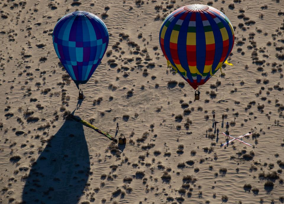 Two hot air balloons come in for a landing Friday in Palm Desert next to a target that pilots compete to drop bean bags on during the annual Cathedral City Hot Air Balloon Festival.