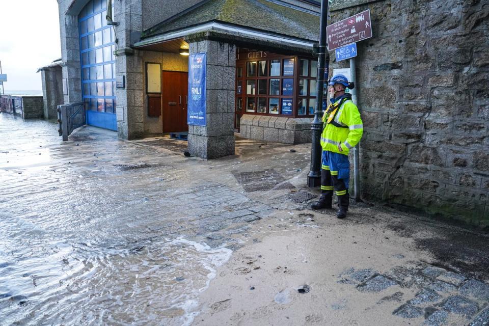 A member of HM Coastguard watches floodwater on the harbourside in St Ives, Cornwall (Getty)