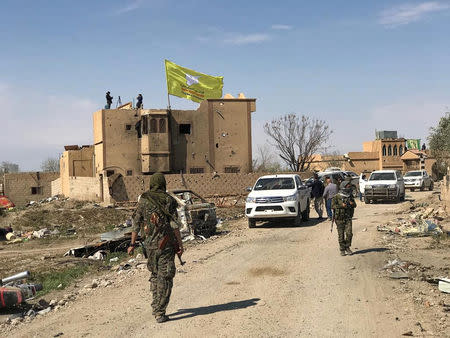 A Syrian Democratic Forces flag flutters on a damaged building in the village of Baghouz, Deir Al Zor province, Syria, March 23, 2019. REUTERS/Stringer