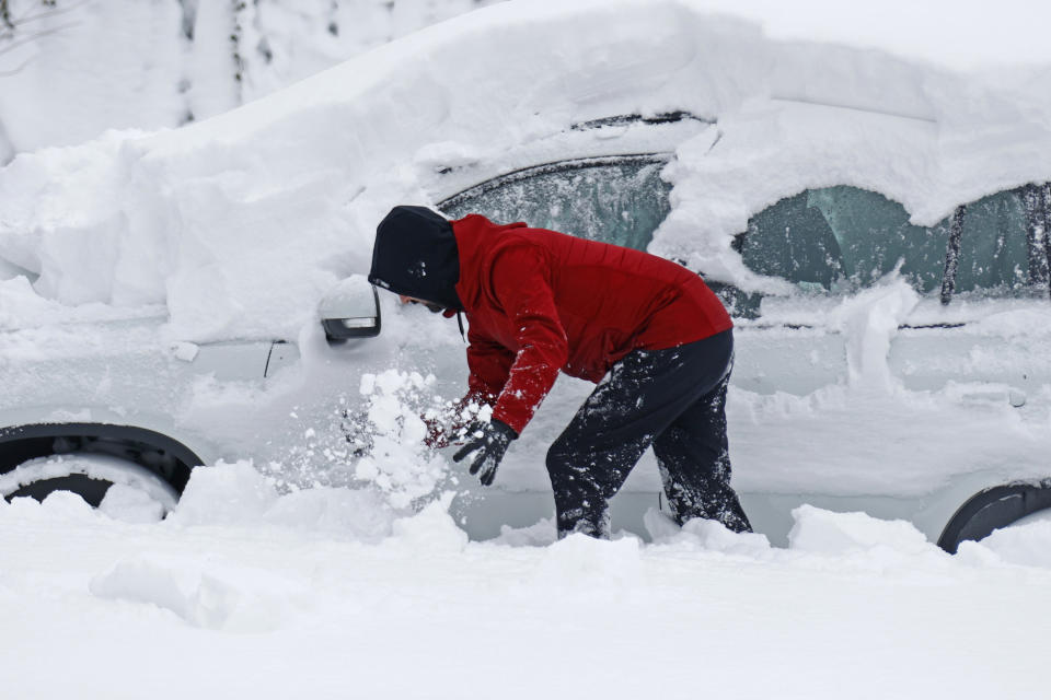 A person clears snow off their car after a winter storm rolled through Western New York Tuesday, Dec. 27, 2022, in Amherst, N.Y. (AP Photo/Jeffrey T. Barnes)