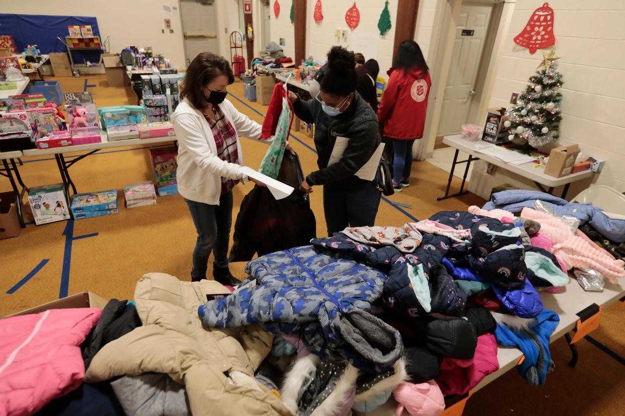 Julie Barcelos, volunteer, gives a woman a hand in packing a bag with clothing she has selected at the annual Neediest Family Fund drive held at the Salvation Army on Purchase Street in New Bedford in this Standard Times file photo.