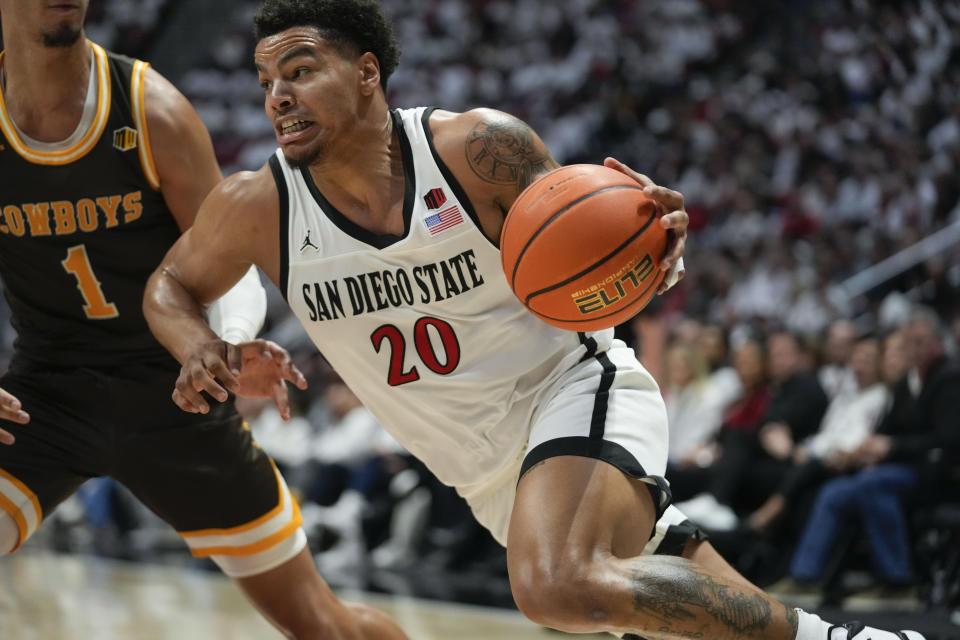 San Diego State guard Matt Bradley (20) drives to the basket at Wyoming guard Brendan Wenzel (1) defends during the second half of an NCAA college basketball game Saturday, March 4, 2023, in San Diego. (AP Photo/Gregory Bull)