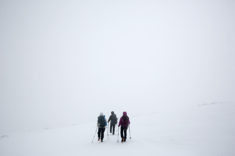 In this Saturday, April 5, 2014 photo, climbers Ania Kowalczyk, Marielle Bergeron and Lucy Bergeron, all of Quebec City, search for a trail marker during a whiteout caused by freezing fog, less than a mile from the summit of Mount Adams in New Hampshire. Winter weather, which often lasts well into spring in the Presidential Range, prompted the group to turn back. (AP Photo/Robert F. Bukaty)