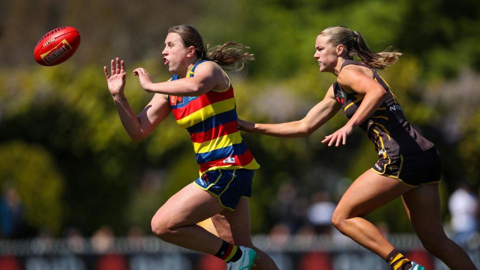 Chelsea Biddell of the Crows chased by Bridie Hipwell of the Hawks.