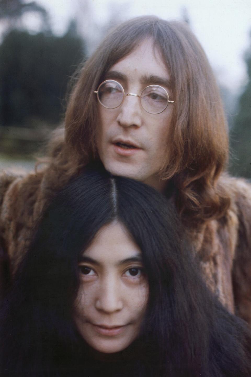 A man wearing glasses rests his chin on top of his wife's head.