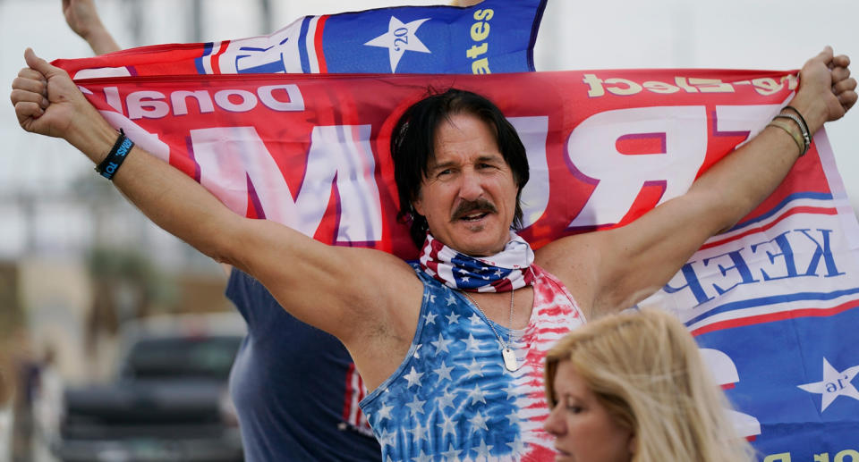 A man holds a holds a Donald Trump sign in a protest against Democrats.