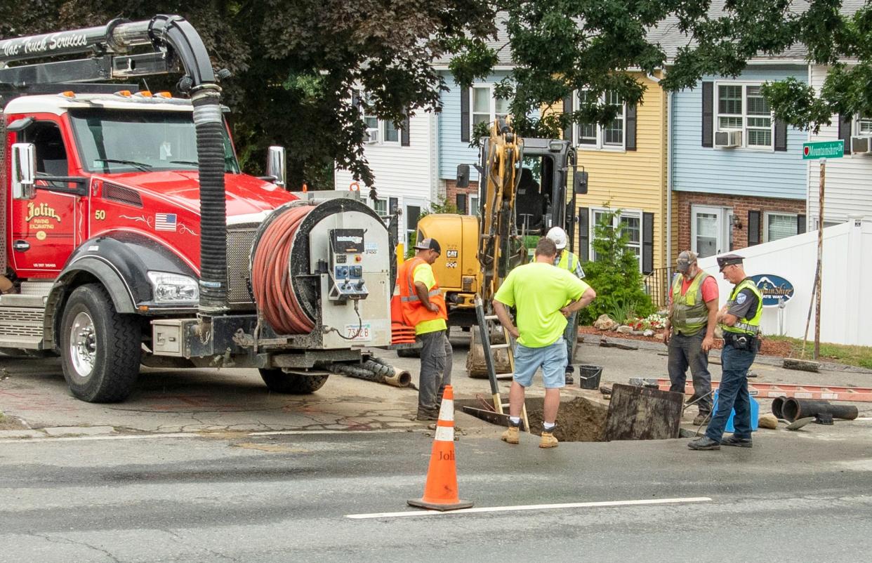 Workers dig to reach a leaking water valve on West Mountain Street on Monday.