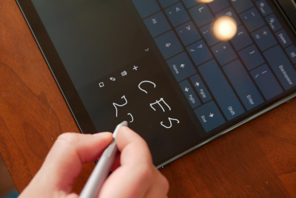 Person writing note on screen of Lenovo Yoga Book 9i.