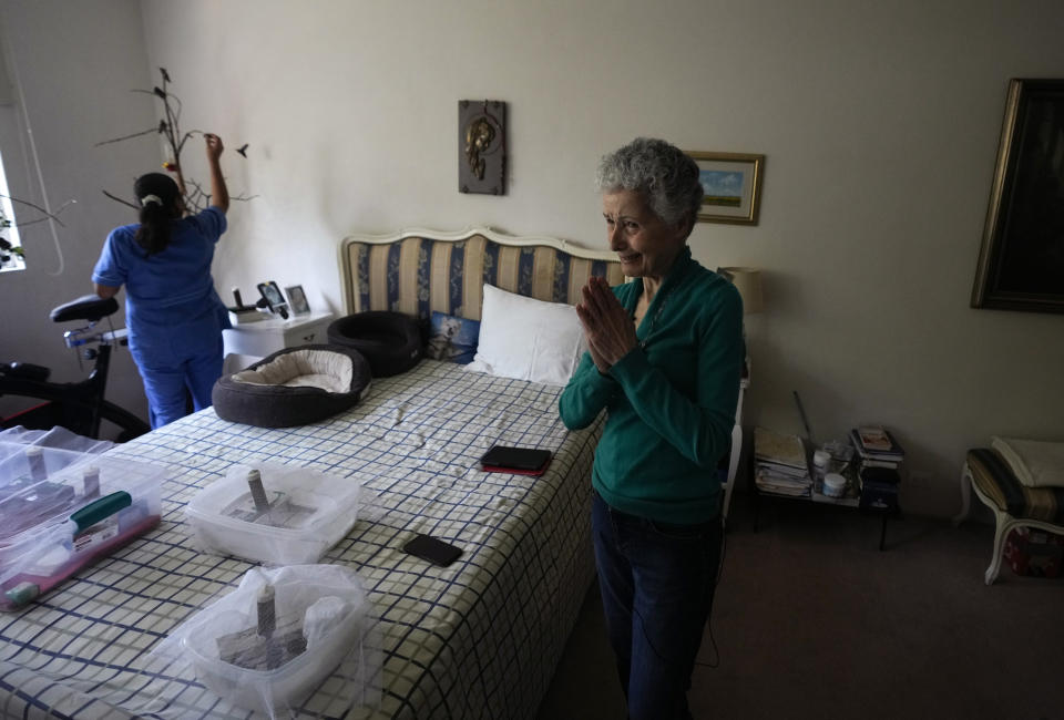 Catia Lattouf agradece a un joven por traerle un colibrí que rescató, mientras su colaboradora Cecilia Santos alimenta a colibríes en el fondo en el apartamento de Lattouf, que se ha convertido en una clínica improvisada para estos pequeños pájaros, en la Ciudad de México, el lunes 7 de agosto de 2023. (AP Foto/Fernando Llano)