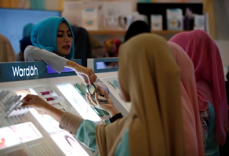 A saleswoman helps visitors at Wardah's cosmetic booth, an Indonesian brand specialising in products for Muslim women, at Indonesia Fashion Week in Jakarta