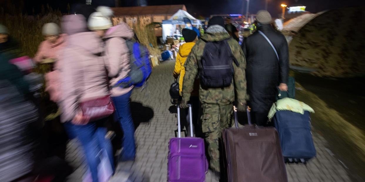A man in camouflage clothing helps refugees from Ukraine to pull their suitcases at the border crossing in Medyka, Poland.