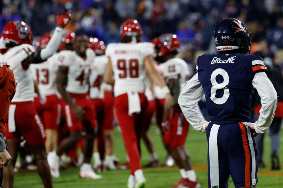 North Carolina State players celebrate as Virginia Cavaliers cornerback Malcolm Greene looks on.