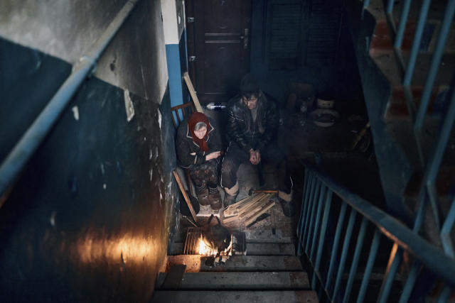 Local residents cook on the stairs of an apartment house in Chasiv Yar, Donetsk region, Ukraine, Monday, March 6, 2023. (AP Photo/Libkos)