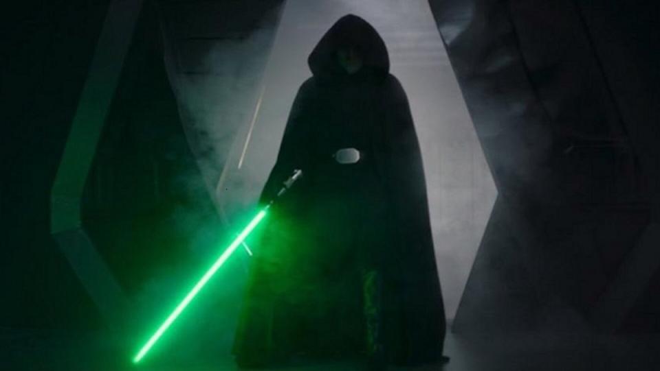 Luke Skywalker in a black robe wields a lightsaber