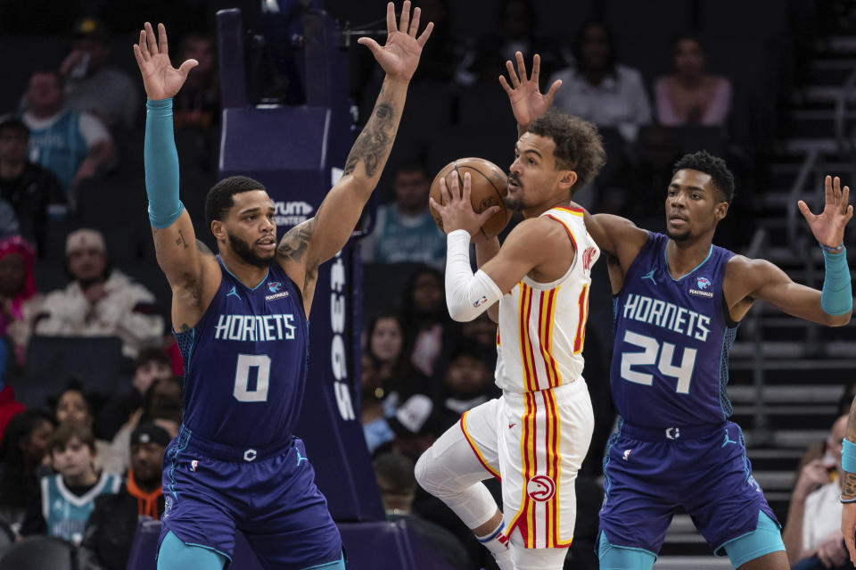 Charlotte Hornets forward Miles Bridges (0) and forward Brandon Miller (24) defend against Atlanta Hawks guard Trae Young during the first half of an NBA basketball game Wednesday, Feb. 14, 2024, in Charlotte, N.C. (AP Photo/Matt Kelley)