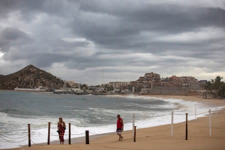 People walk at La Medano beach in Cabo San Lucas as Hurricane Lorena churns close to the southern tip of Mexico's Baja California peninsula