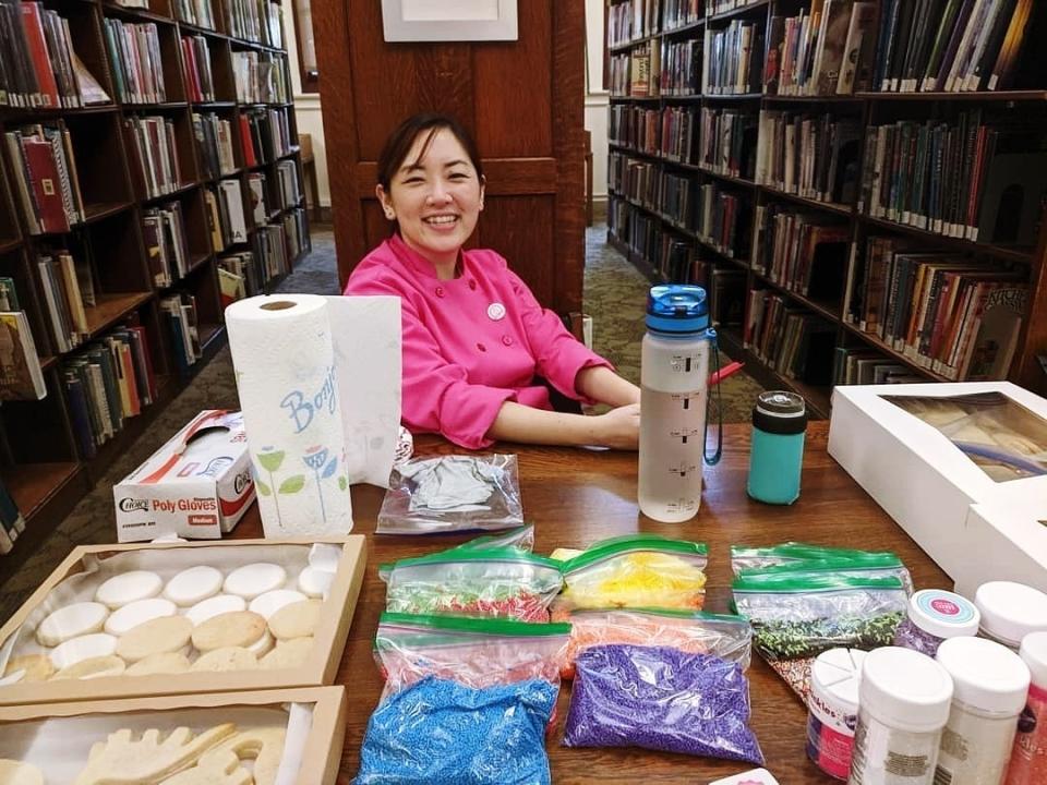 In this Oct. 29, 2019, photo, provided by Itha Cao, Jasmine Cho sits with all her cookie decorating supplies at a census awareness event at the Carnegie Library in Pittsburgh. The coronavirus has waylaid efforts to get as many people as possible to take part in the census. Pittsburgh had commissioned Cho, who uses cookie decorating to highlight Asian American and social justice issues, to lead decorating workshops with a census theme. An October session drew almost 50 people and grabbed attention, but workshops planned for March and April were canceled. (Courtesy of Jasmine Cho via AP)