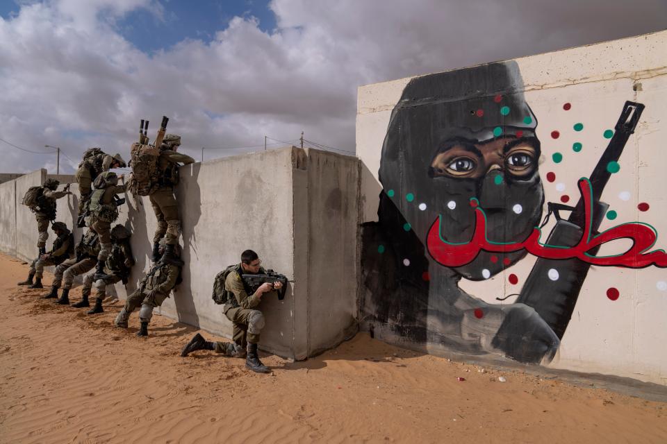 Israeli soldiers climb on a wall as they conduct a mock assault during an urban warfare exercise at an army training facility, at the Zeelim army base, southern Israel, Jan. 24, 2022.