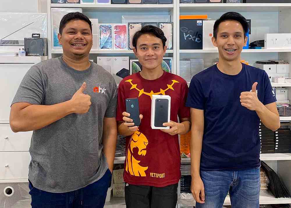 Phone seller Muhammad Asyraf Ab Rahim (left) decided to give Hafizuddin Gos Hambali (centre) a brand new gadget after reading about his academic achievements online. — Picture from Twitter/hafizuddingh