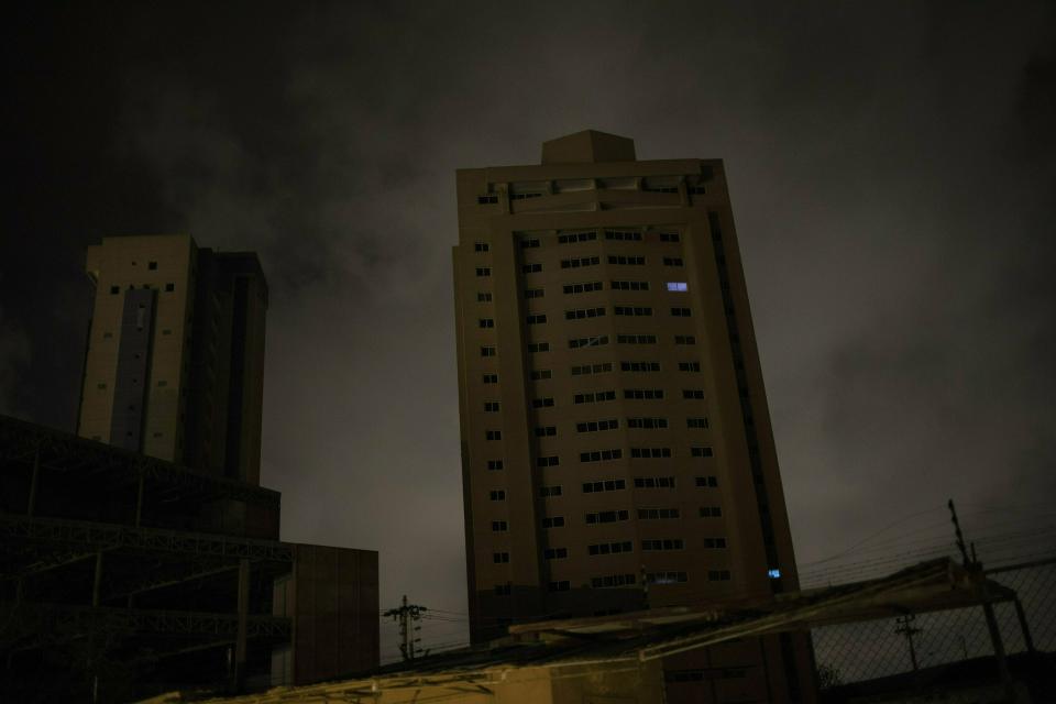 In this May 23, 2019 photo, only two apartments of a building are illuminated by electric generators during a black out in Maracaibo, Venezuela. Some have opted for small generation units costing a few hundred dollars that can pump out enough power to run a few appliances at a time, such as using the lights and water heater for a shower. (AP Photo/Rodrigo Abd)