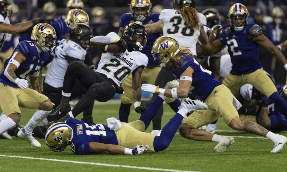 Colorado running back Deion Smith is stopped by Washington defensive back Asa Turner, right, linebacker Daniel Heimuli, on turf, and defensive back Zakhari Spears left, during the first half of an NCAA college football game Saturday, Nov. 19, 2022, in Seattle. (AP Photo/Stephen Brashear)