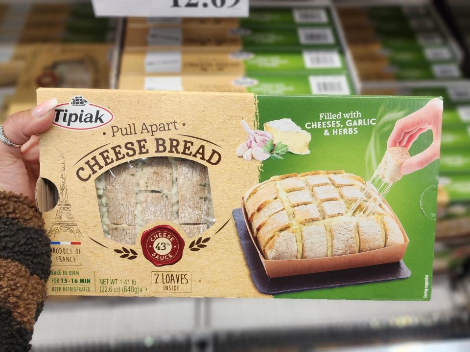 Hand holding brown and green box of Tipiak pull-apart cheese bread