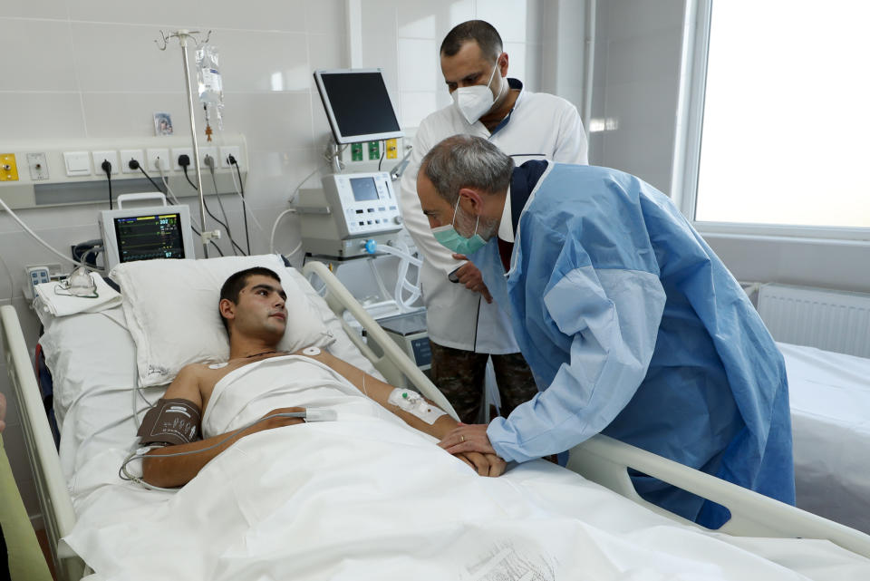 In this photo provided by the Armenian Prime Minister Press Service via PAN Photo, Armenian Prime Minister Nikol Pashinyan speaks to a wounded serviceman as he visits a military hospital in Yerevan, Armenia, Friday, Oct. 23, 2020. Heavy fighting is raging over Nagorno-Karabakh even as top diplomats from Armenia and Azerbaijan have traveled to Washington for negotiations on settling the neighboring countries’ decades-long conflict. (Tigran Mehrabyan, Armenian Prime Minister Press Service/PAN Photo via AP)