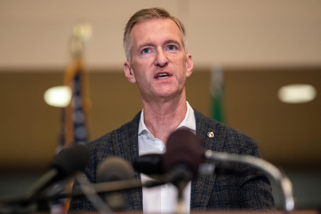 Portland Mayor Ted Wheeler speaks in behind a cluster of microphones