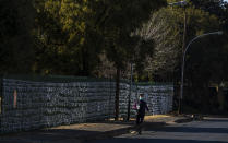 FILE - In this July 29, 2020, file photo, a woman wearing a face mask to protect against the spread of the coronavirus, walks past ribbons tired onto the fence to represent South Africans who have died from COVID-19, at St James Presbyterian church in Bedford Gardens, Johannesburg, South Africa. Africa’s confirmed coronavirus cases have surpassed 1 million, but global health experts tell The Associated Press the true toll is several times higher. Whatever Africa’s real coronavirus toll, the church has quietly been marking the country’s “known” number of deaths by tying white ribbons to its fence. The project's founders say each ribbon really stands for multiple people. (AP Photo/Themba Hadebe, File)