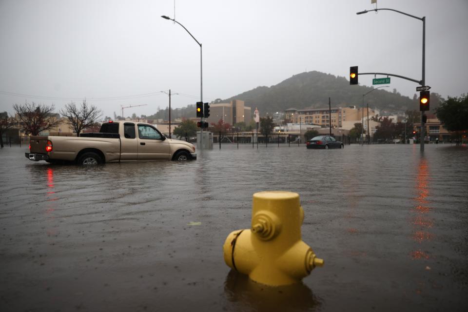 Cars try to navigate a flooded street on Oct. 24, 2021 in San Rafael, Calif. A Category 5 atmospheric river is bringing heavy precipitation, high winds and power outages to the San Francisco Bay Area. The storm is expected to bring anywhere between 2 to 5 inches of rain to many parts of the area. 