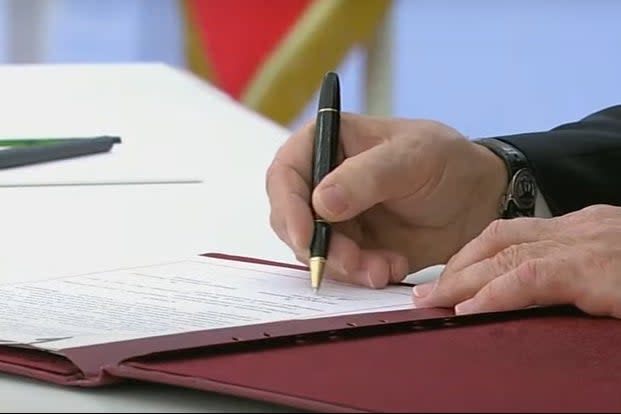 Vladimir Putin signs the document (Sky News)