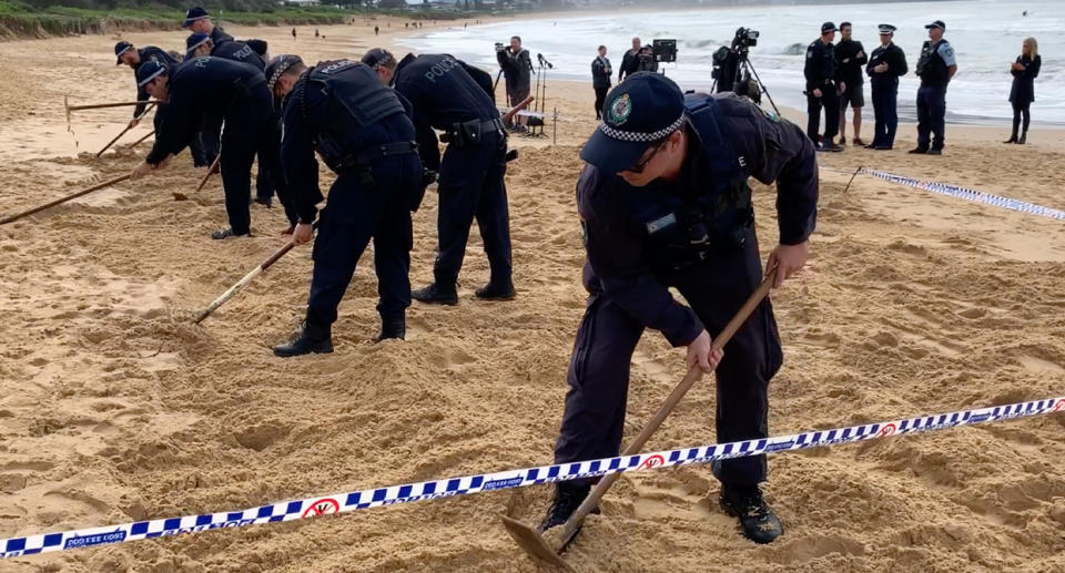 NSW Police officers dig in the sand at Umina Beach after what is believed to be a human jaw bone was found.