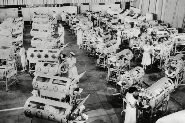 <p>Everett/Shutterstock</p> Stock photo of nurses attending to a room full of patients in iron lungs